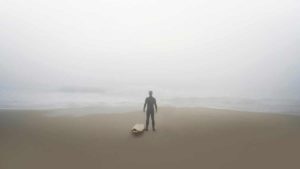 Surfer on the Beach at dawn, looks out at the fog covered ocean